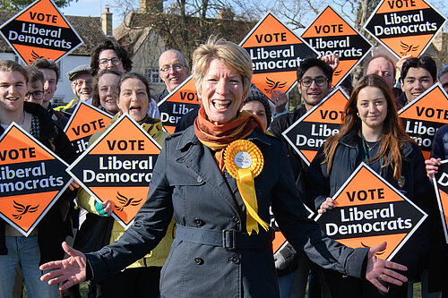 Photo showing Pippa Heylings in front of a large group of Lib Dem supporters holding banners